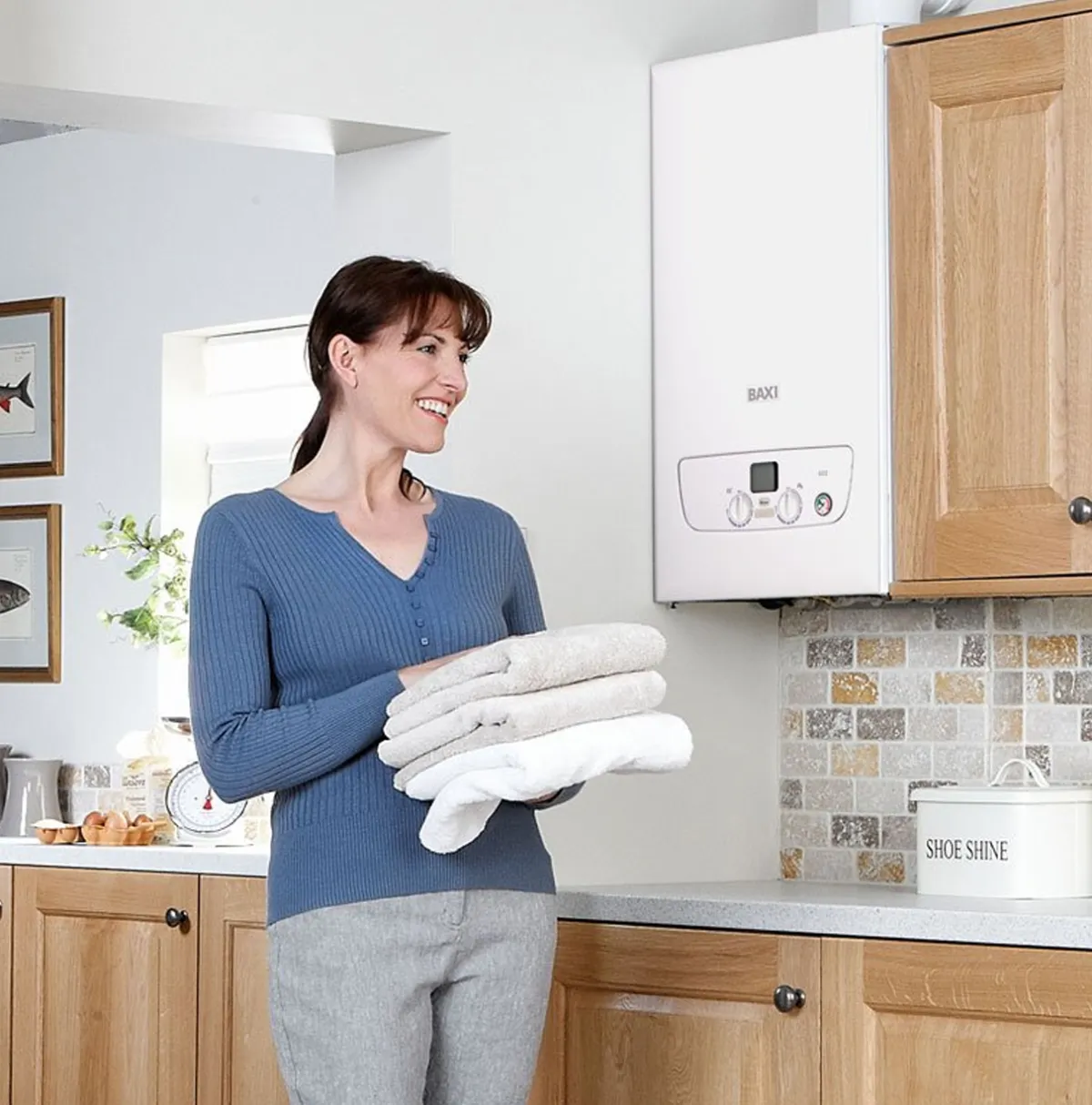 Woman in her kitchen next to a wall-mounted Baxi boiler